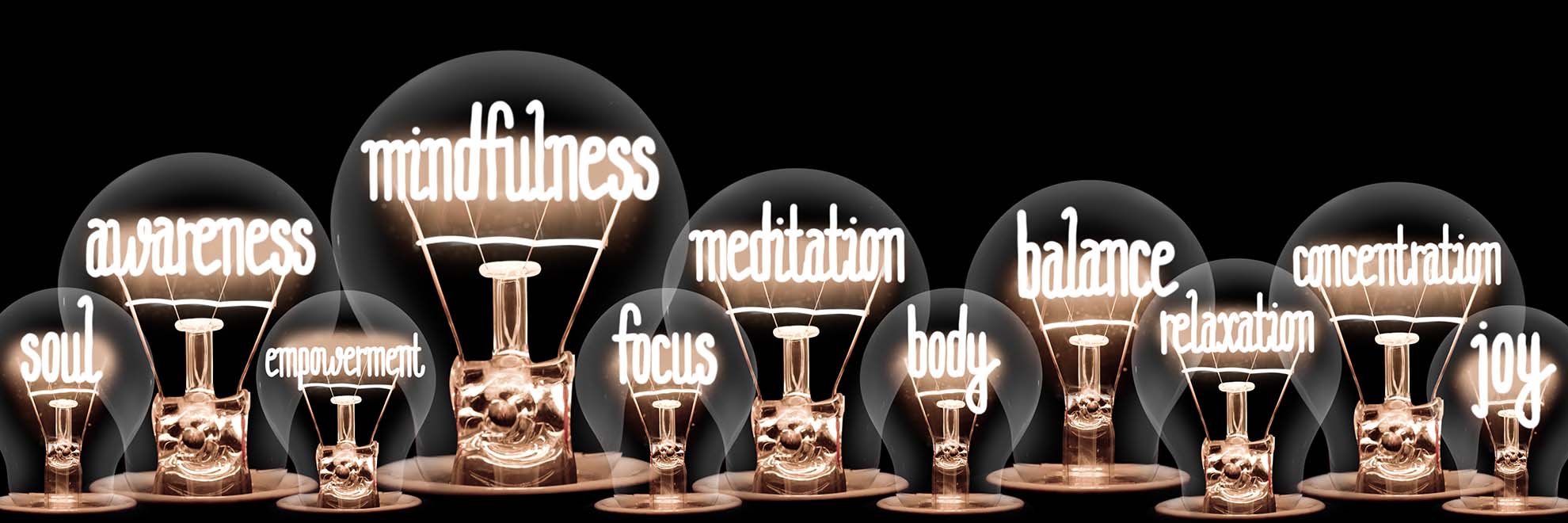 Group of light bulbs with shining fibers in a shape of Mindfulness, Meditation, Balance, Awarness, Body and Soul concept related words isolated on black background.